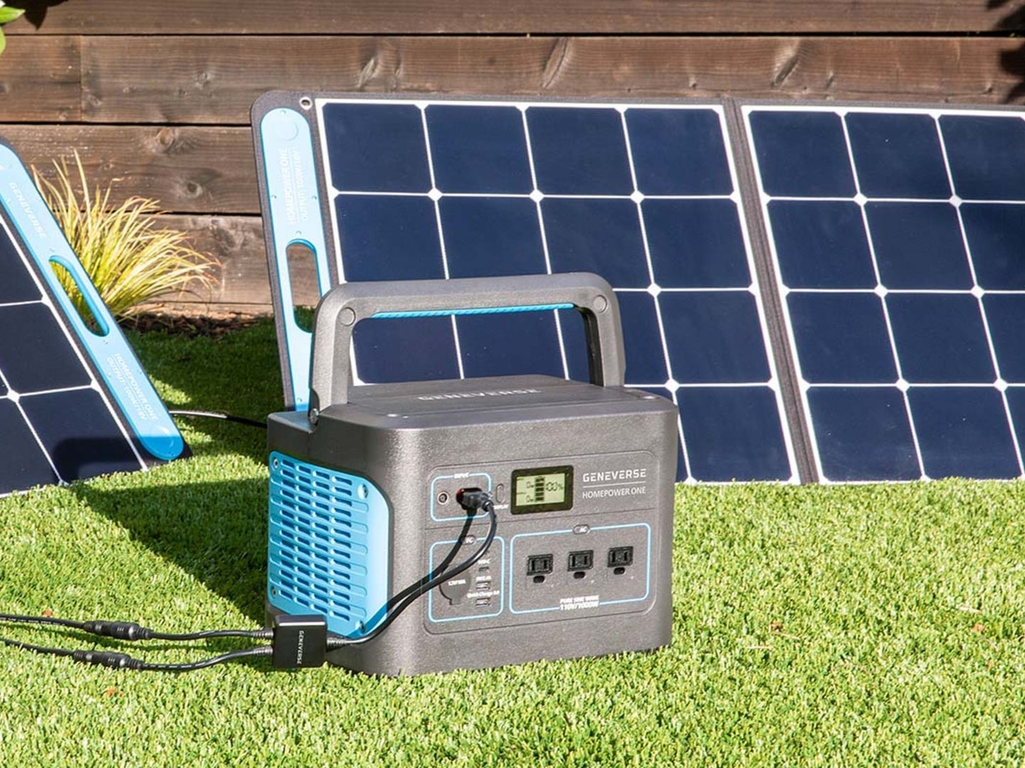 A solar generator and solar panel sit in a backyard