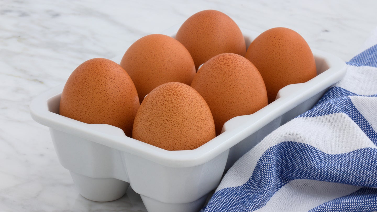 A half dozen eggs sitting on a marble kitchen counter