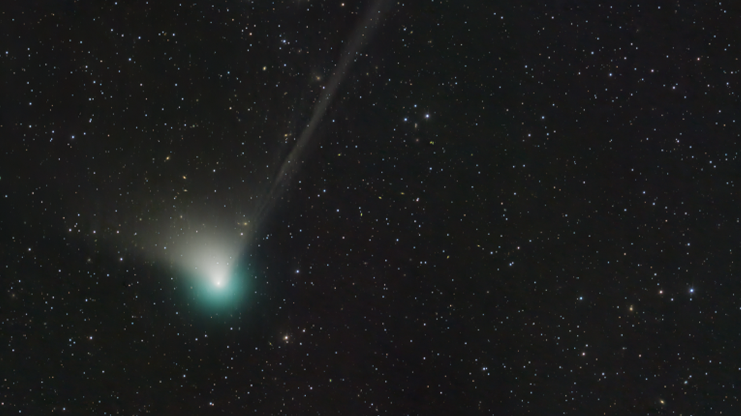 A green tailed comet streaks across the night sky.