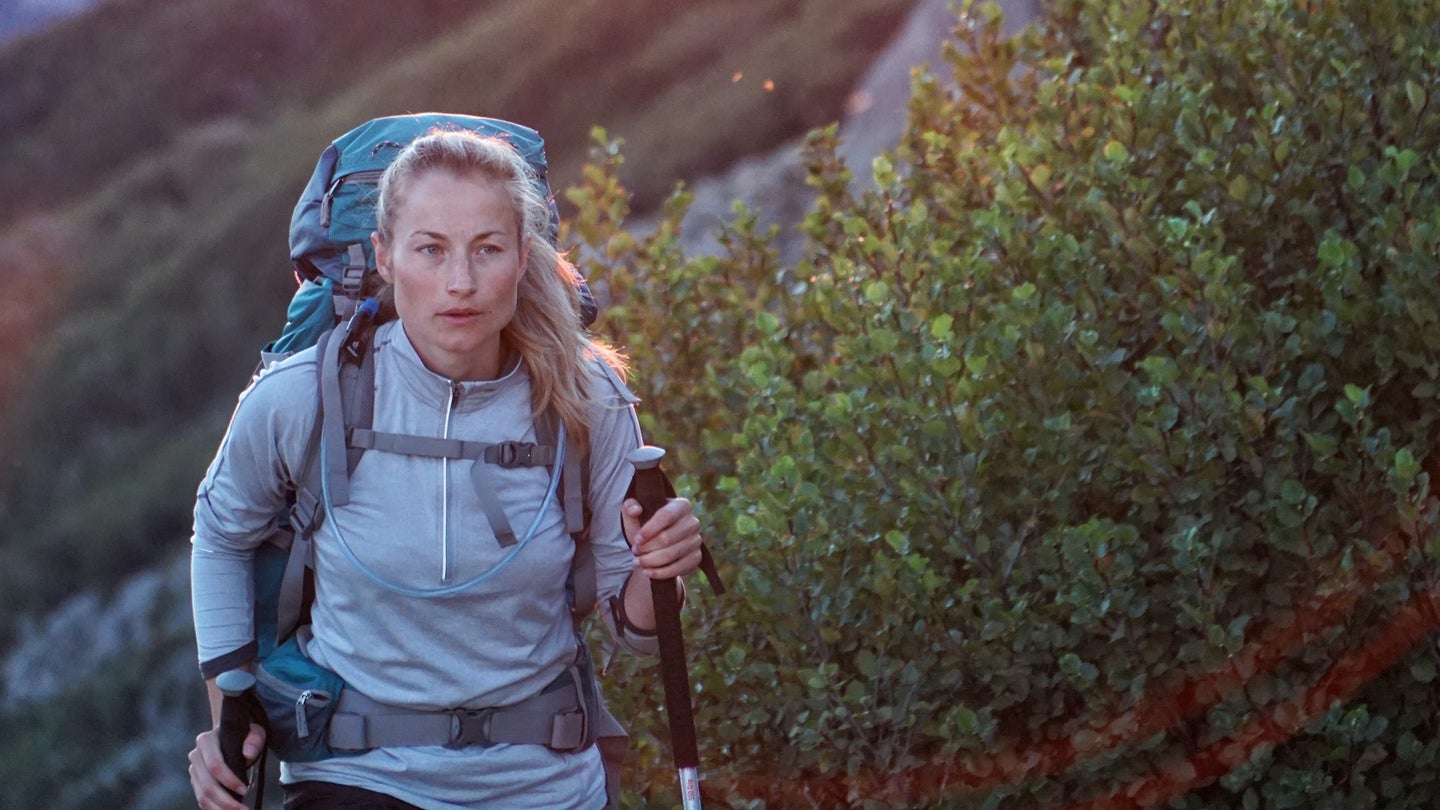 person hiking with backpack and hiking sticks