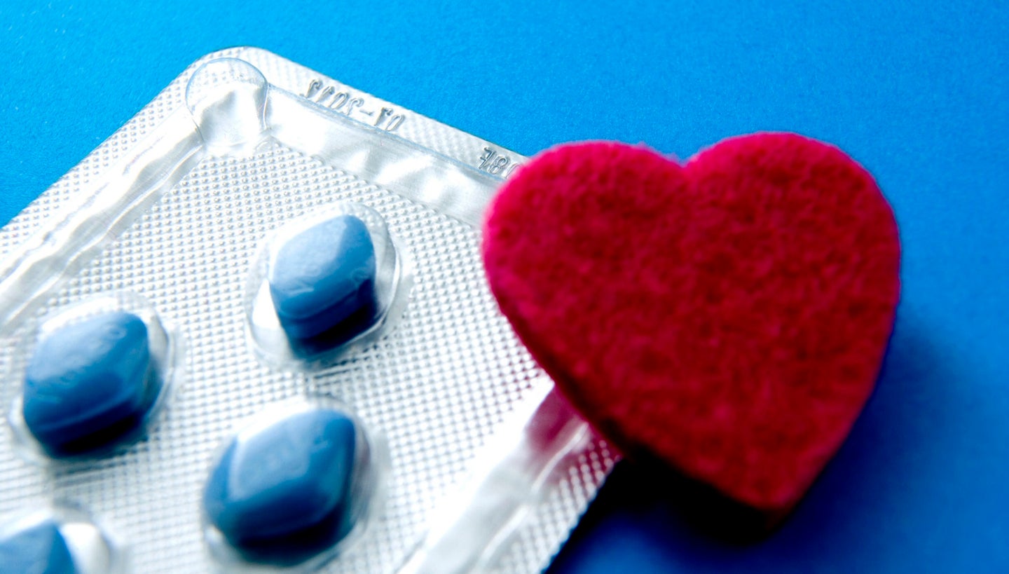 Viagra blue pills next to a felt red heart to show cardiac health benefits from erectile dysfunction drugs