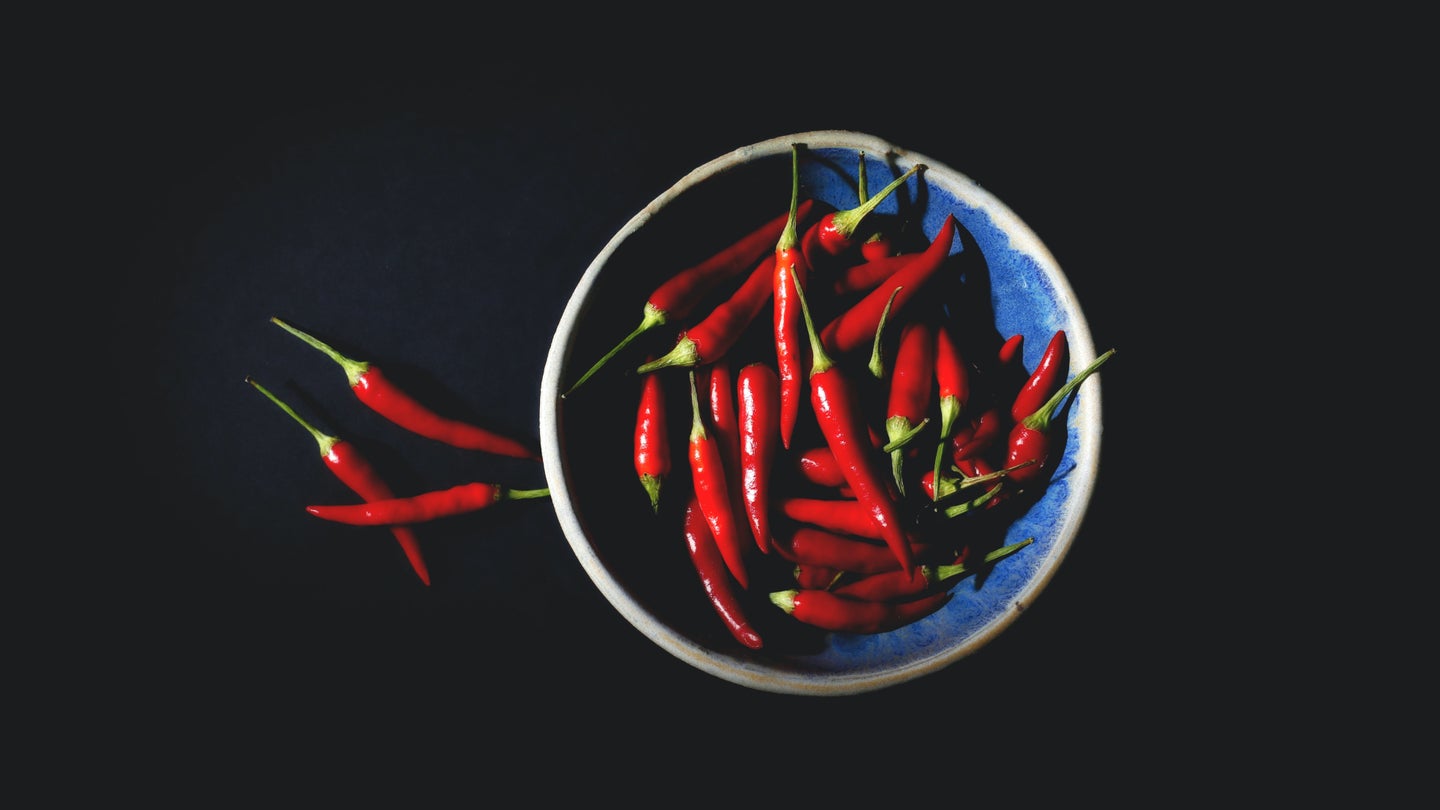 Chilis in a bowl against a black background, perfect for a spicy hot sauce recipe.