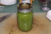 Mild green hot sauce in a mason jar on a cutting board, the result of a homemade hot sauce recipe.
