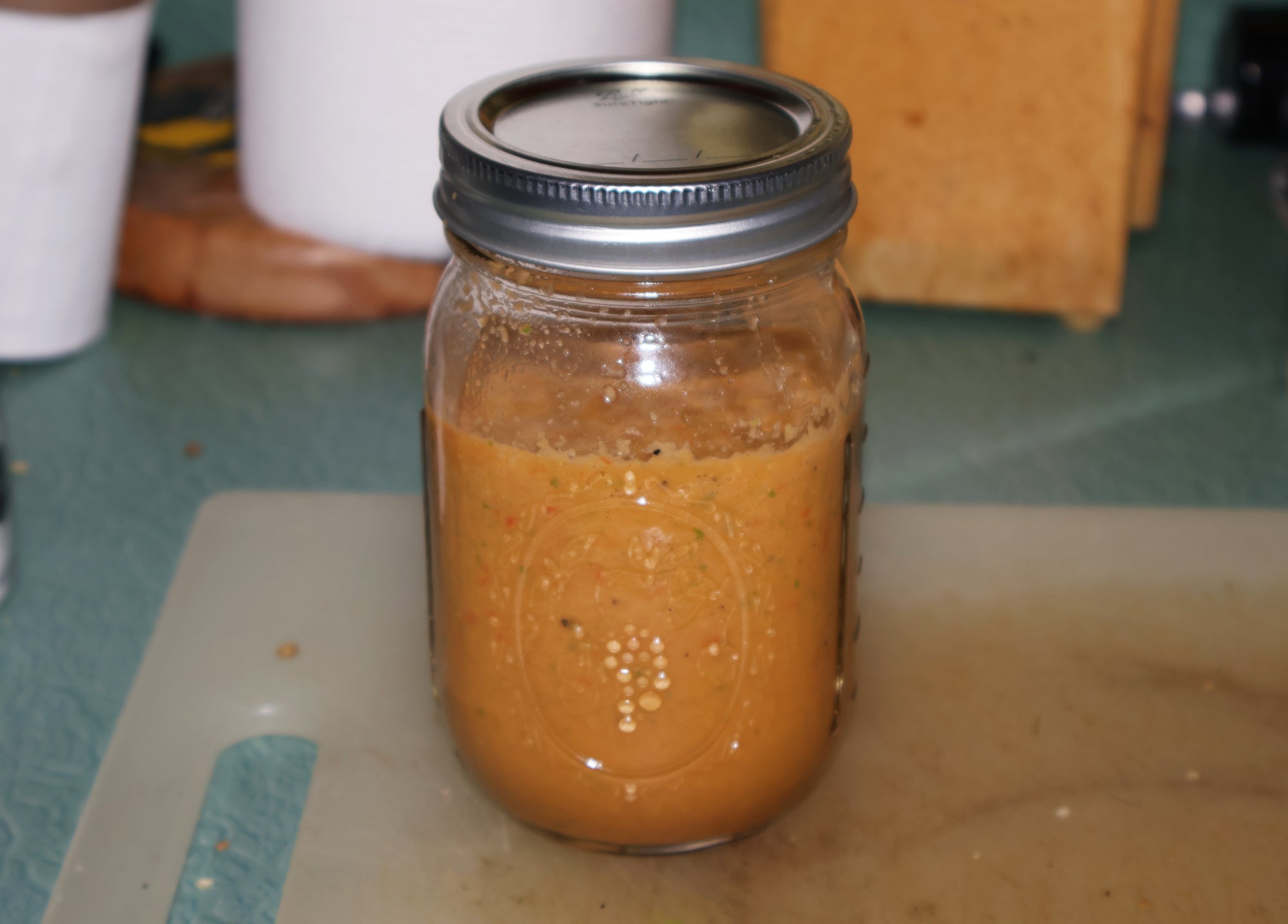 A mason jar full of spicy red hot sauce, from a homemade hot sauce recipe.