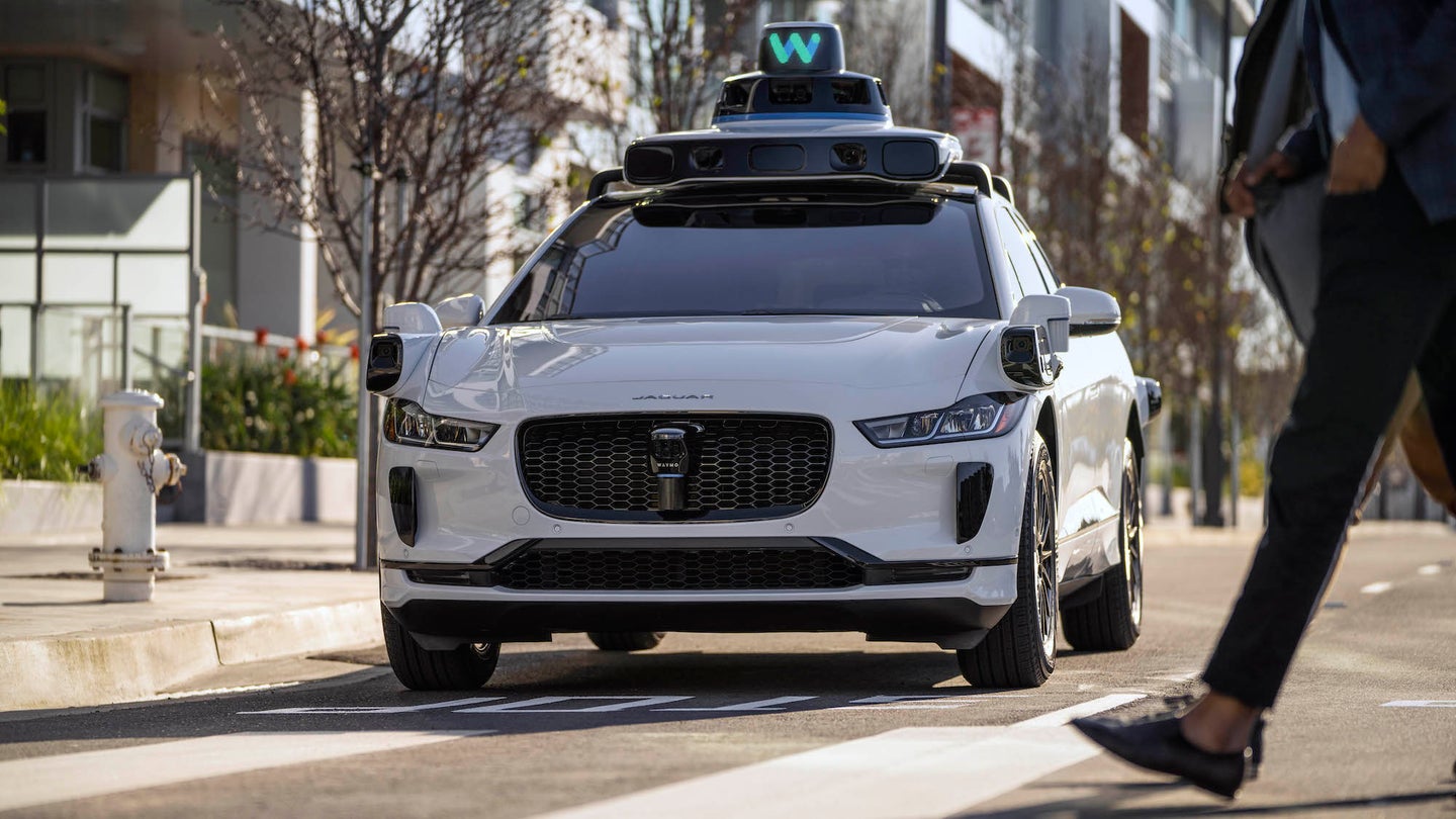 Press photo of Waymo self-driving car waiting at intersection for pedestrians