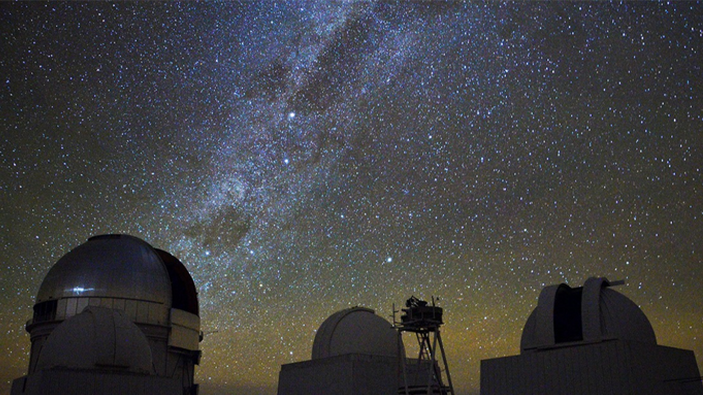 Two giant, circular ground telescopes with an overlay of a starry night sky.