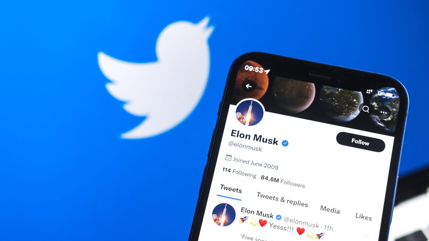 Elon Musk Twitter account on smartphone screen against Twitter logo background