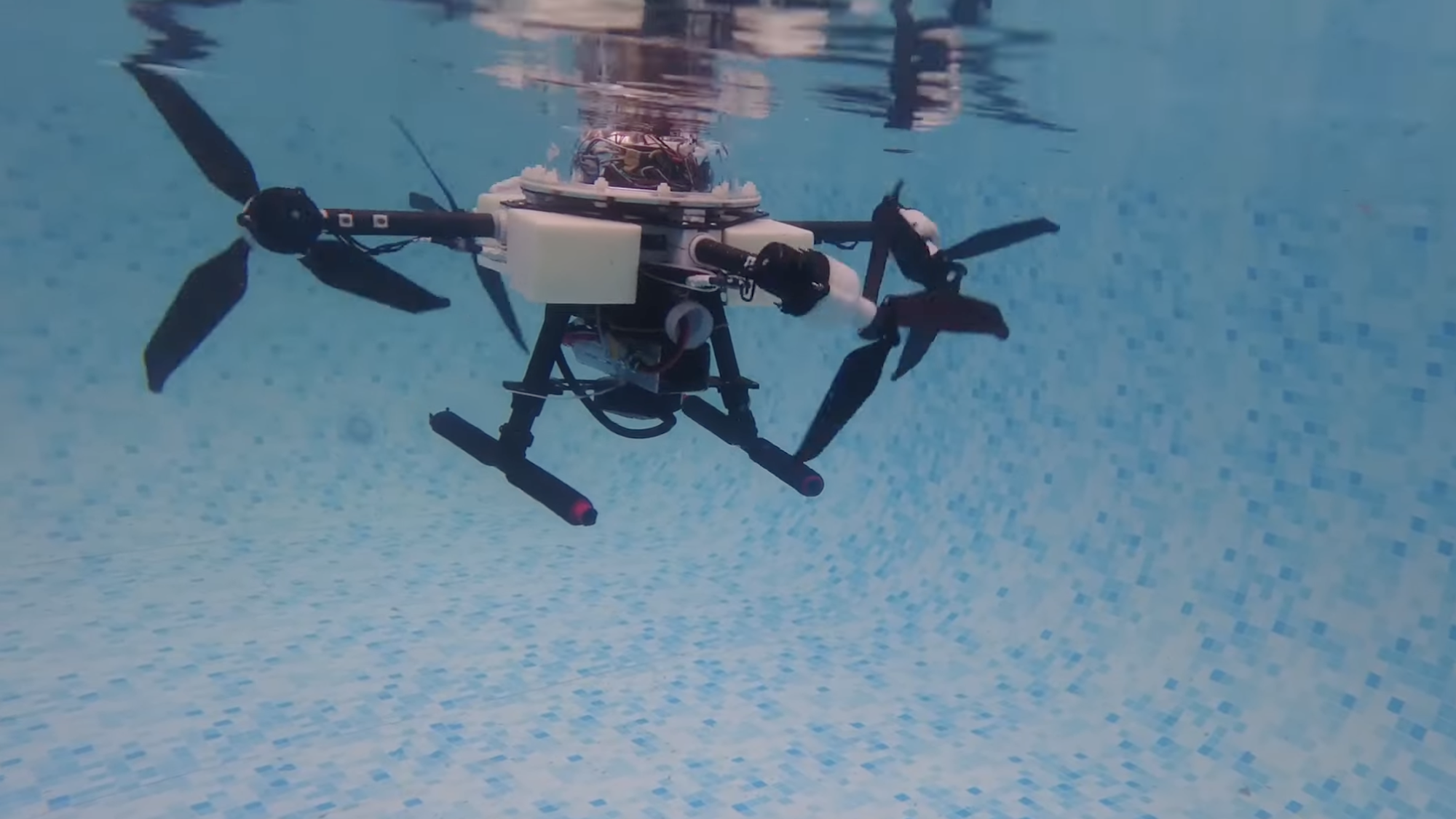 Quadcopter drone propelling itself underwater in swimming pool