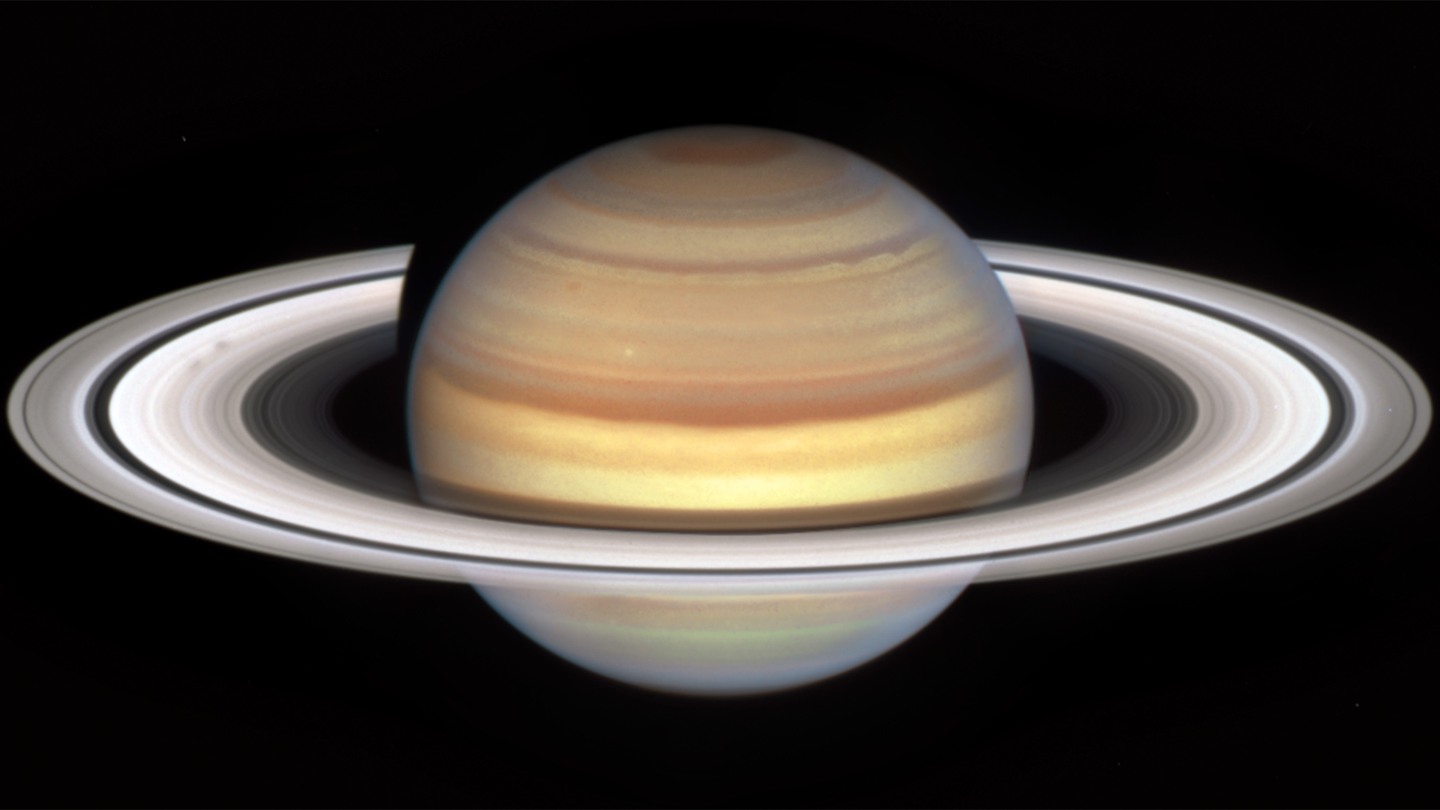 The planet Saturn on a dark background. Two smudgy spokes are seen in the B ring (left). The shape and shading of spokes can appear light or dark, depending on the viewing angle, and sometimes appear more like blobs than classic radial spoke shapes, as seen here.