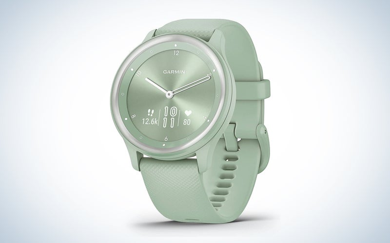 A green Garmin vivomove hybrid sports watch on a blue and white background