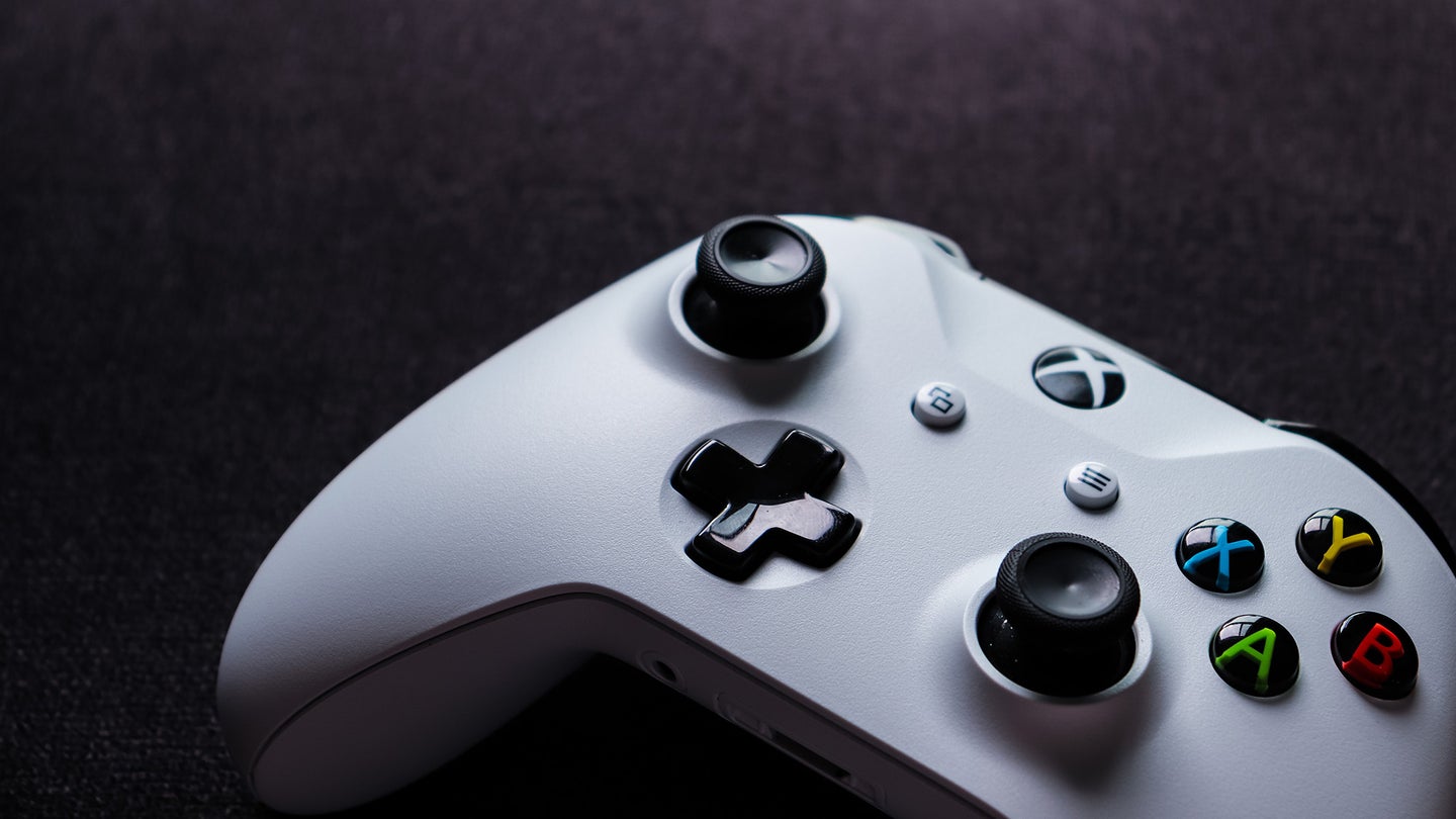 Close up to a white Xbox controller on a black table.