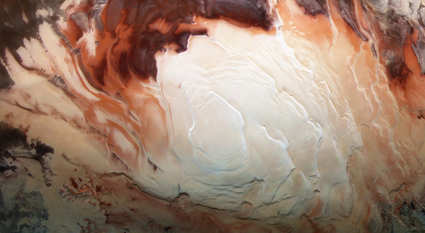 The icy white south pole of Mars, with red soil all around.
