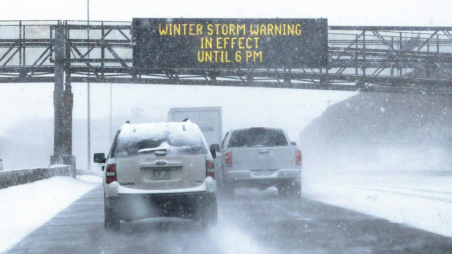 A sign warning of snow and ice conditions, reading " Winter Storm Warning in Effect until 6 pm" is seen on a highway in St. Paul, Minnesota, on February 22, 2022.