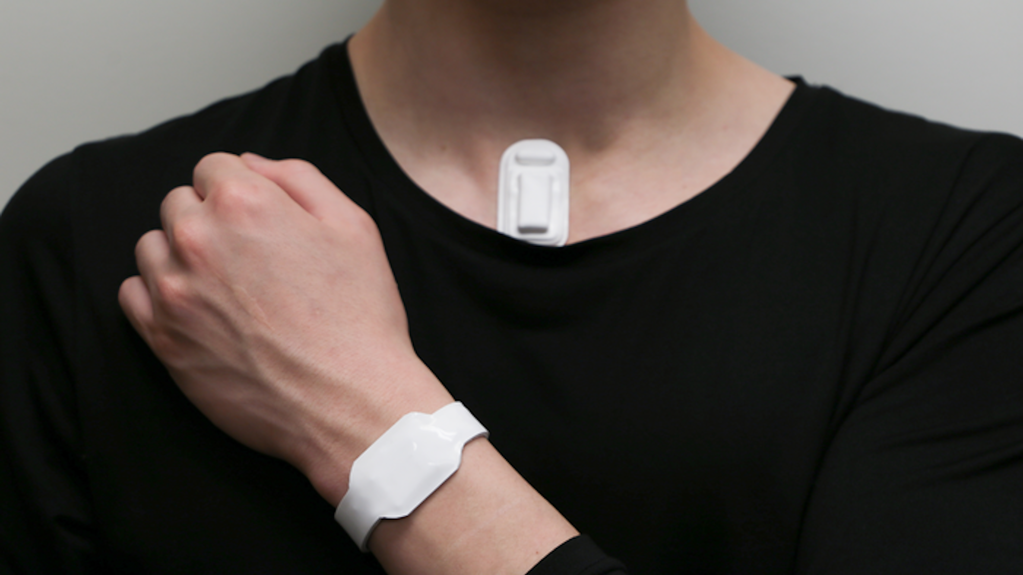 Close up of person wearing vocal strain monitor and haptic wrist device