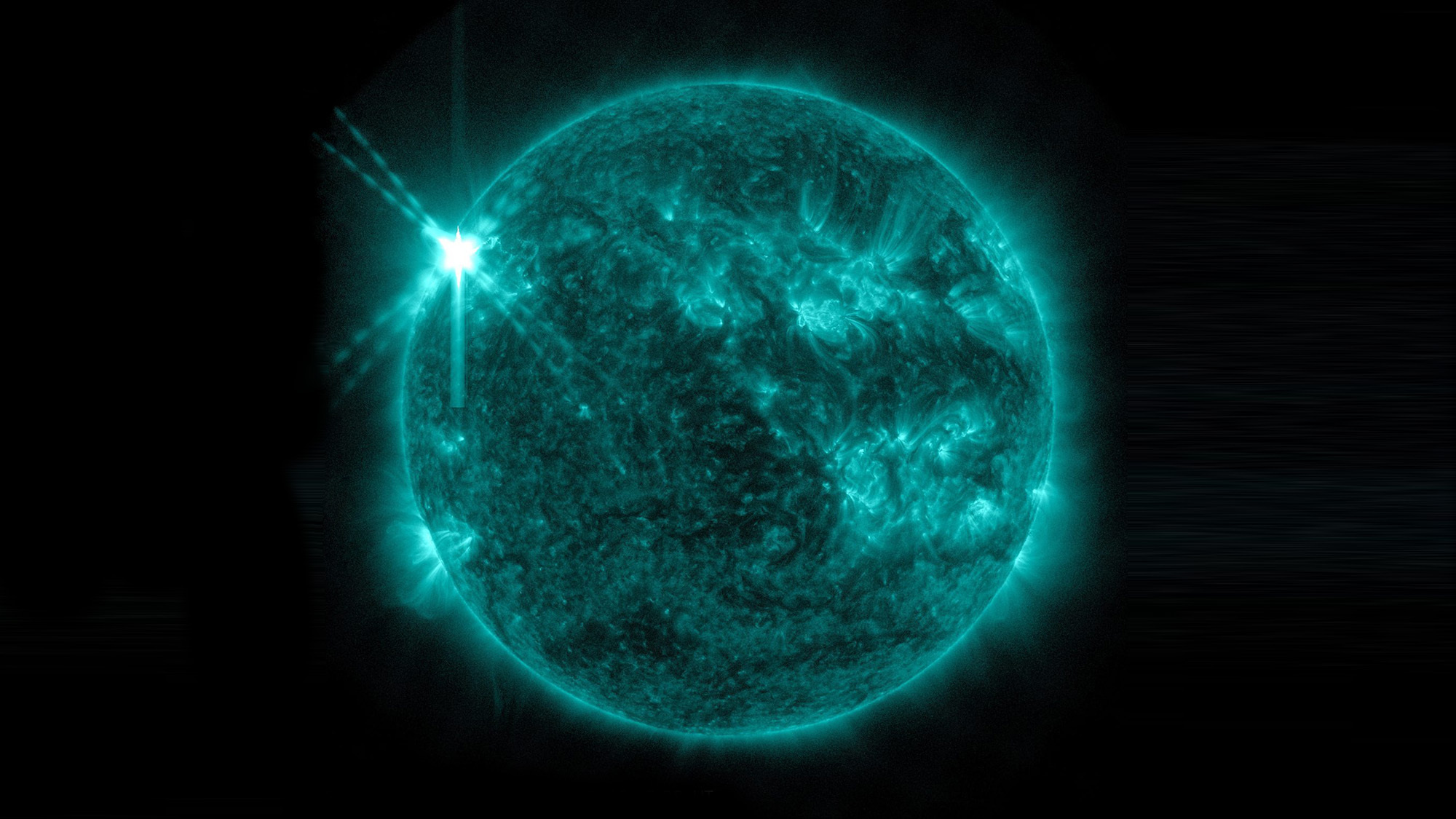 Solar flare shooting out from left side of the sun seen in ultraviolet blue through NASA Solar Dynamics Observatory
