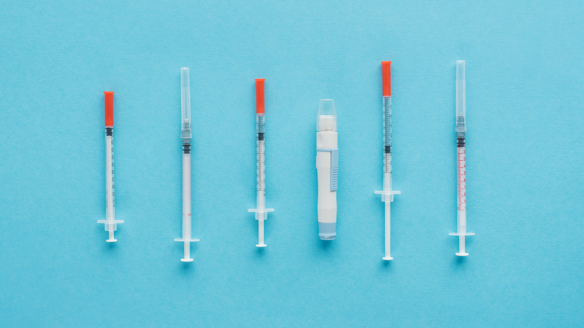Diabetes medicines and injectables on a plain blue background