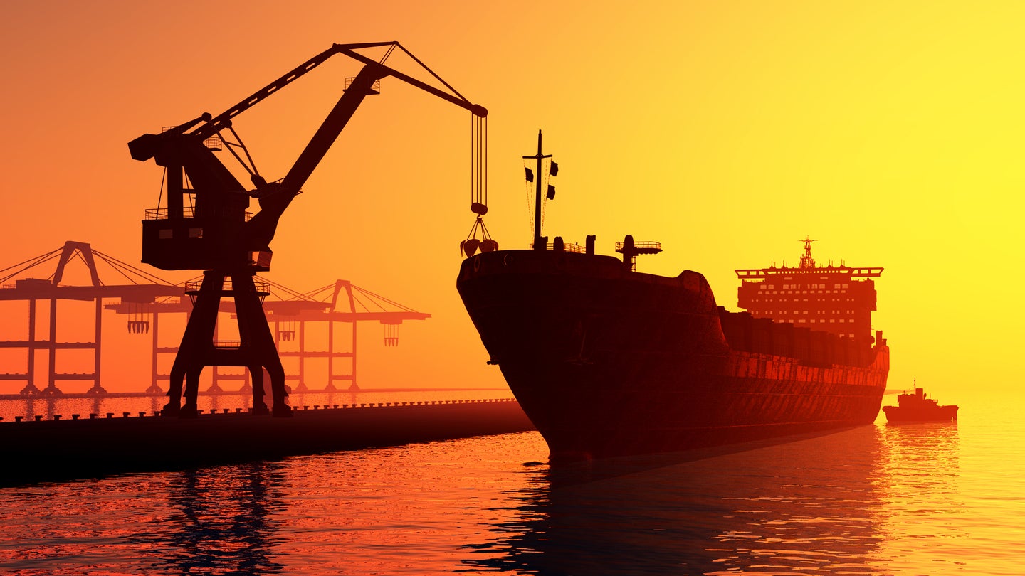 Crane loading cargo onto ship at sunset