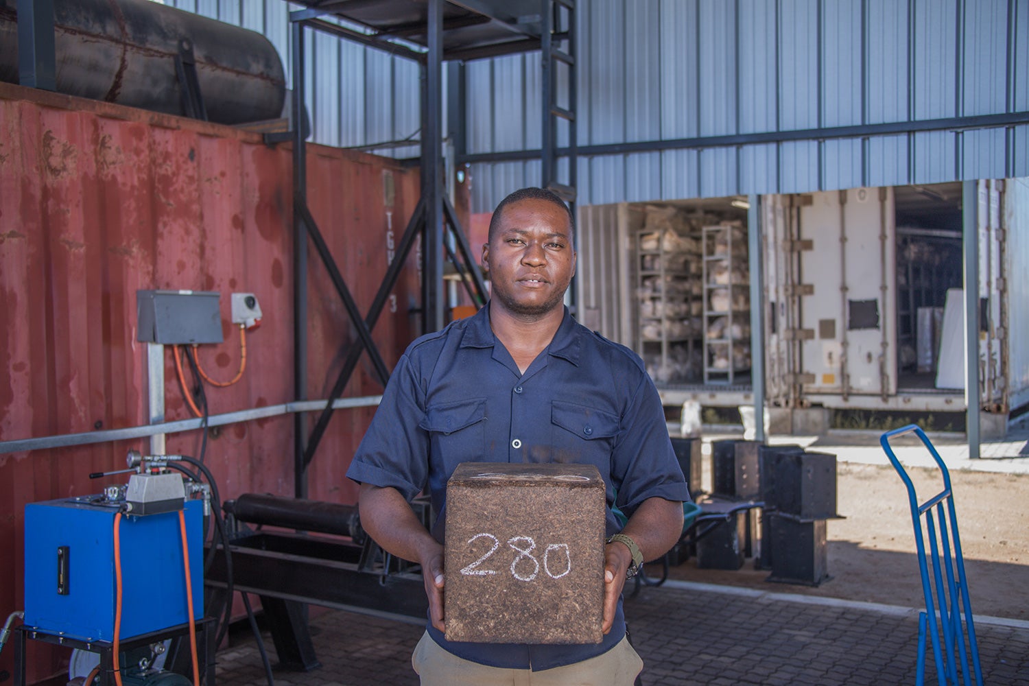 Man in blue shirt in warehouse holding a brick of compressed mycelium