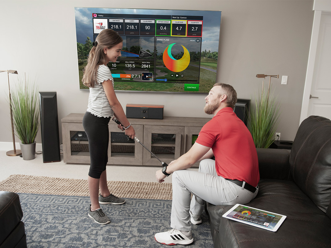 A father and daughter using a golf simulator