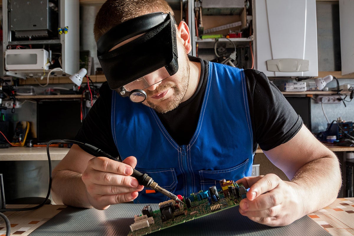 A person wiring a component to a circuit board