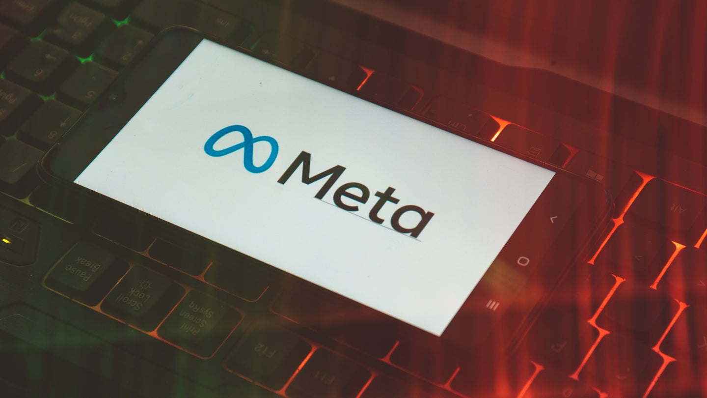 Meta logo on smartphone resting atop glowing keyboard