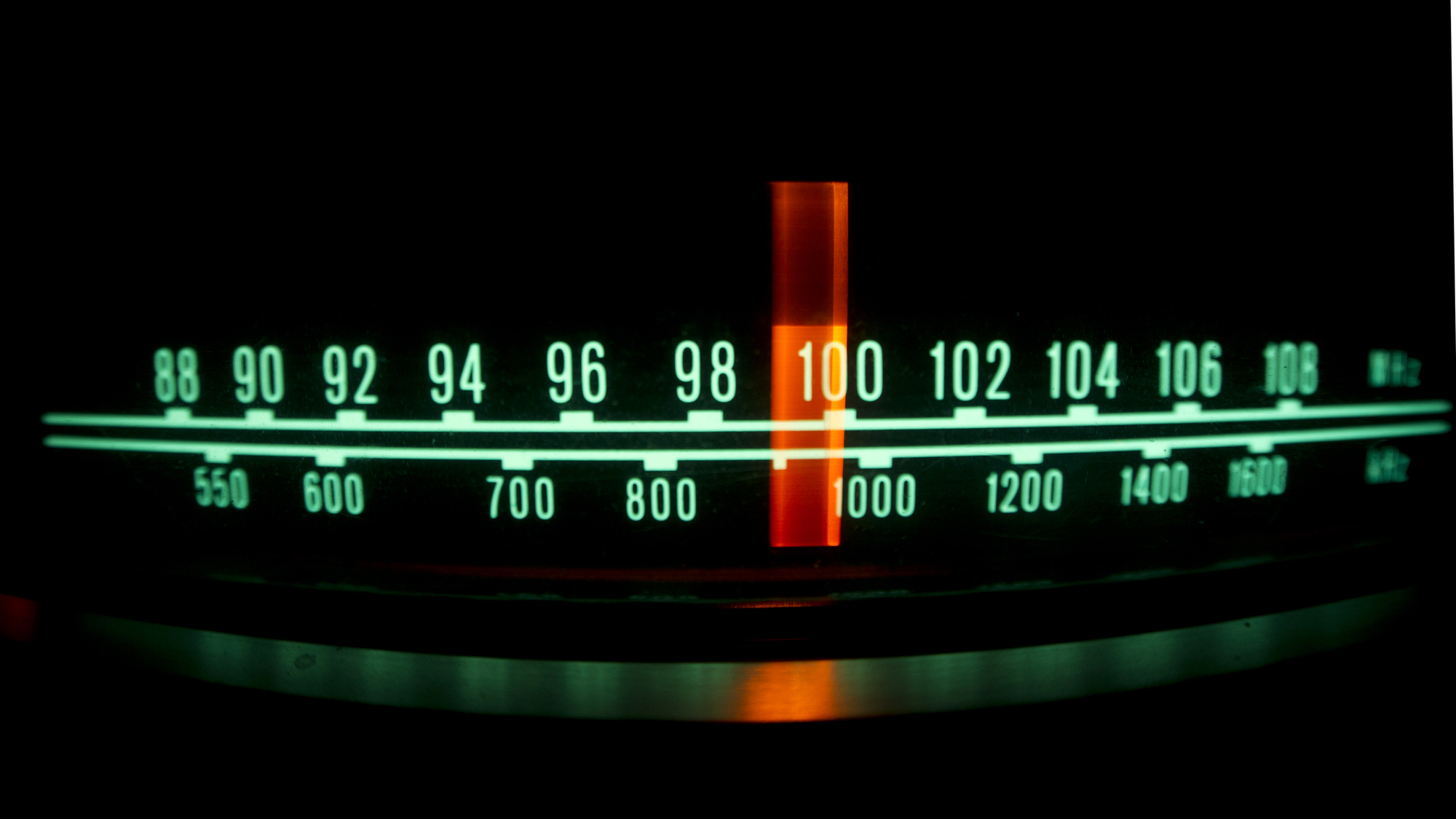 Backlit radio dial showing the marker running through different stations and frequencies