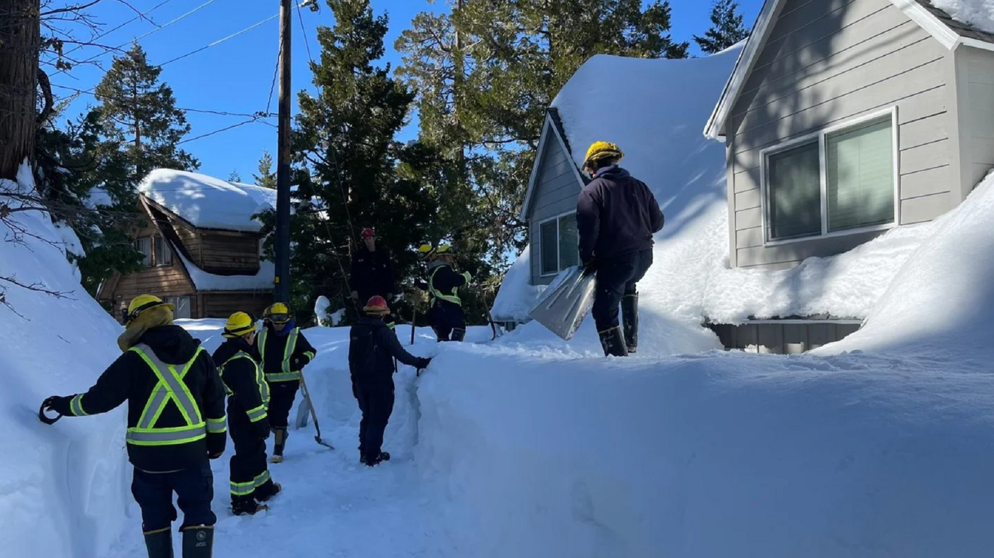 California National Guard members in safety vests and hard hats checking on houses and people buried in snow