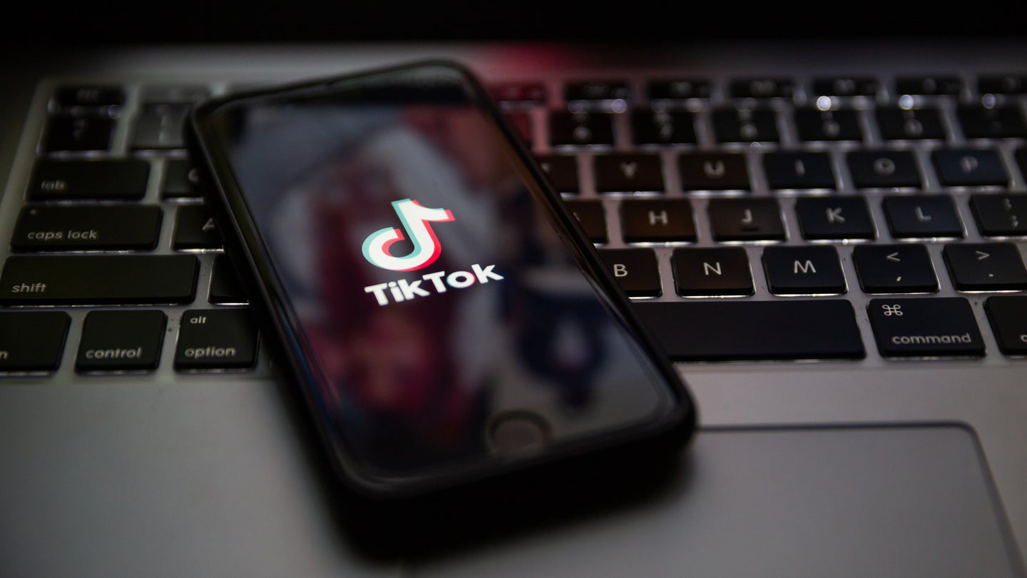 Smartphone with TikTok brand logo resting on laptop laptop keyboard