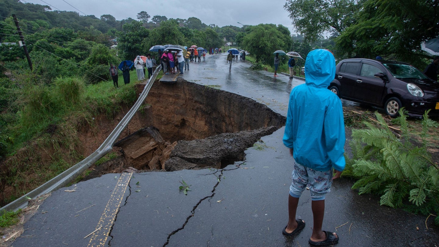 A child stands by a collapsed road caused by flooding waters due to heavy rains following Cyclone Freddy in Blantyre, Malawi, on March 13, 2023.
