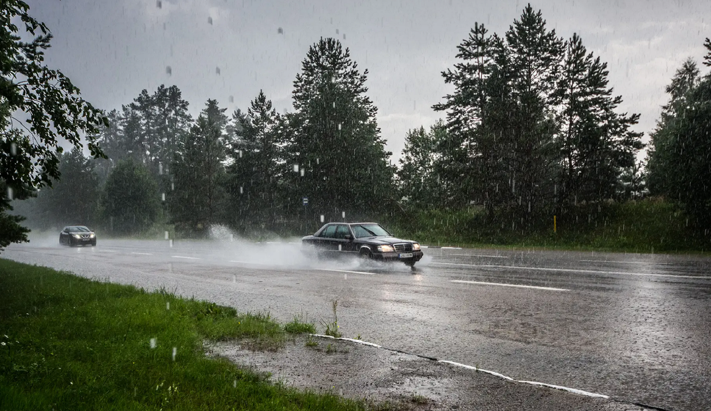 Black Mercedes Benz sedan hydroplaning in rain when speeding down highway