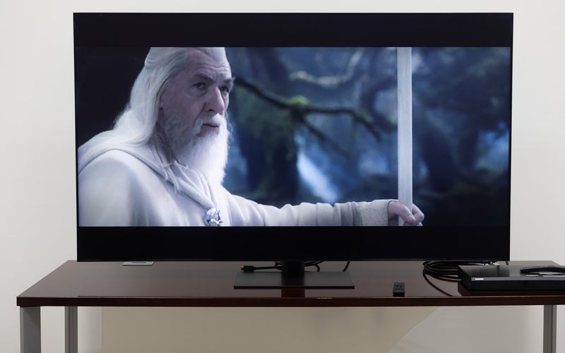 The Samsung QN90C TV on a stand in a room showing the Lord of the Rings.