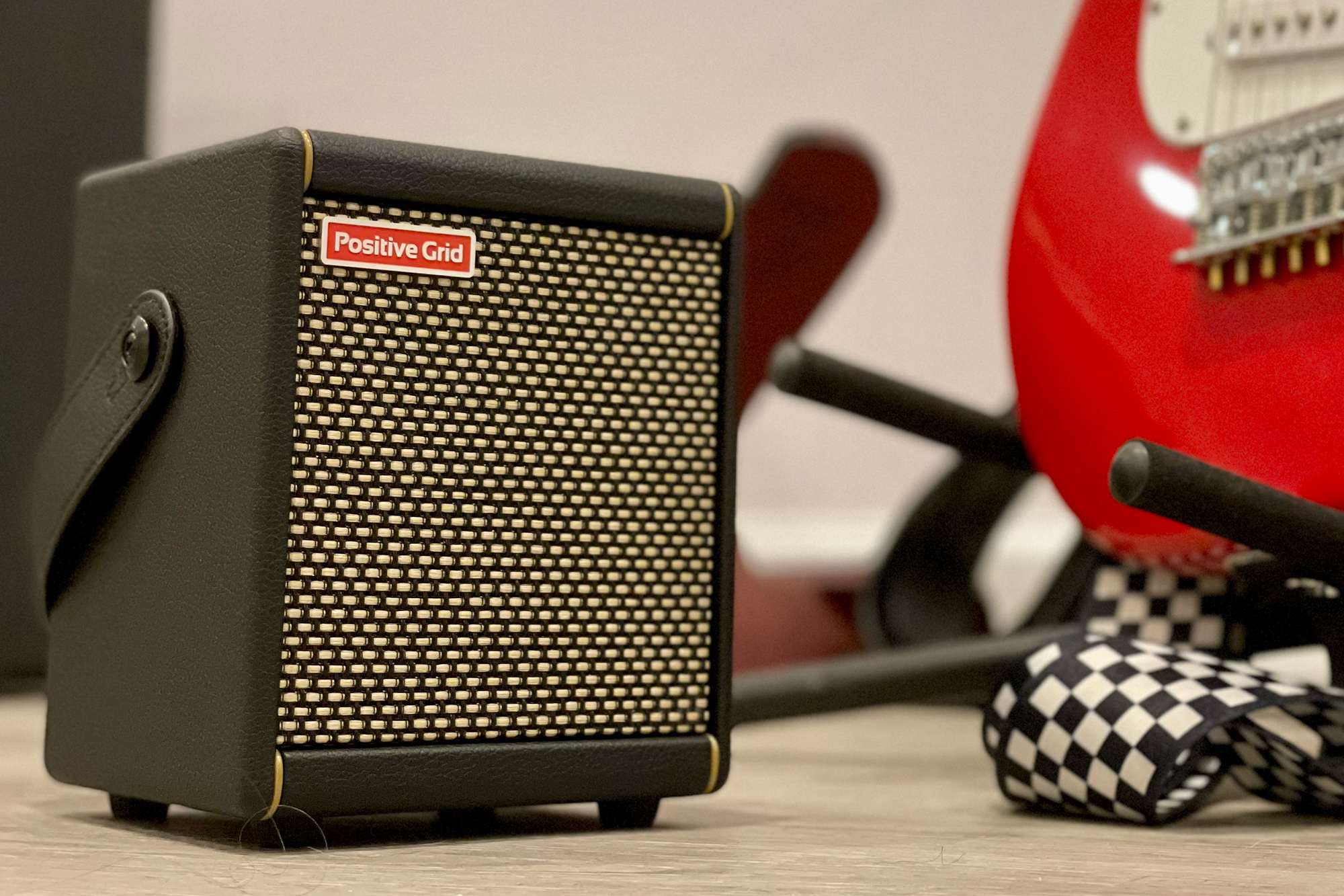 Positive Grid Spark Mini practice amp Bluetooth speaker on the floor next to a red guitar