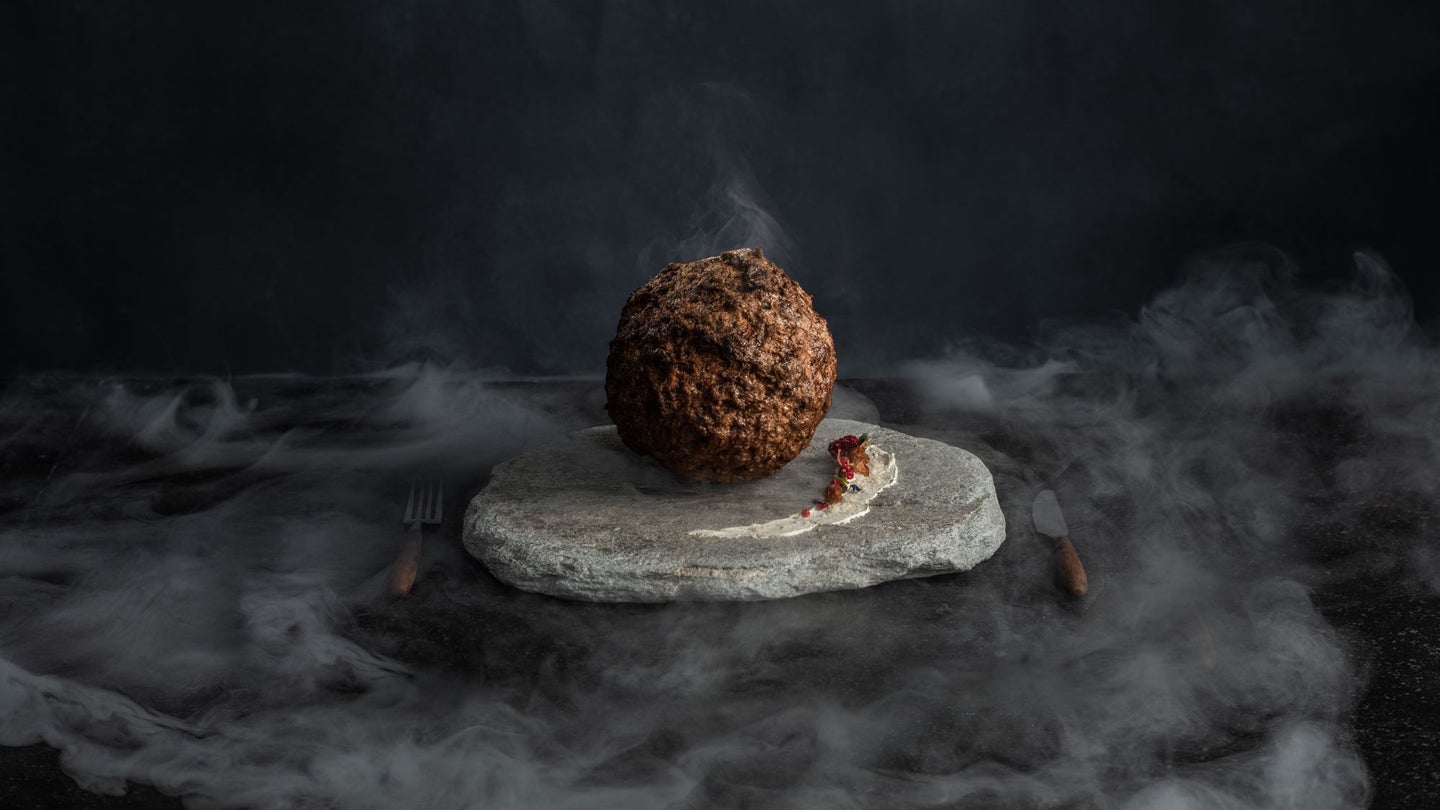 Woolly mammoth meatball on stone plate atop smoky table