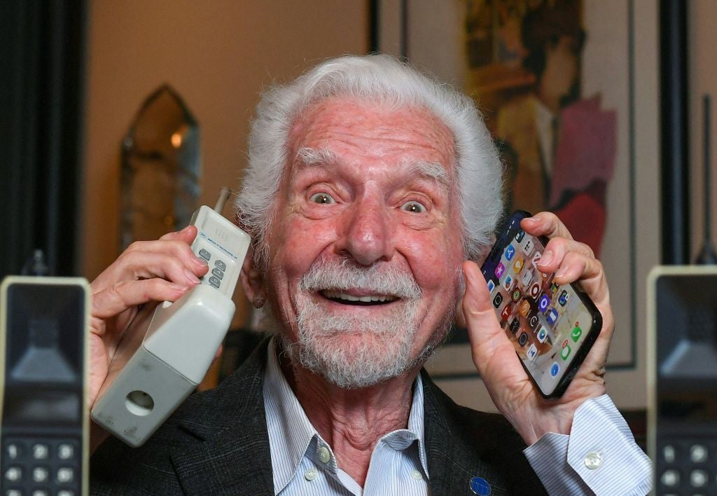Engineer Martin Cooper holds in his right hand a contemporary copy of the original cell phone he used to make the first cell phone call on April 3, 1973, in Del Mar, California on March 20, 2023. - The problem with mobile phones is that people look at them too much. At least, that's according to the man who invented them 50 years ago. Martin Cooper, an American engineer dubbed the "Father of the cell phone," says the neat little device we all have in our pockets has almost boundless potential and could one day even help conquer disease. But right now, we can be a little obssessed. (Photo by VALERIE MACON / AFP) (Photo by VALERIE MACON/AFP via Getty Images)