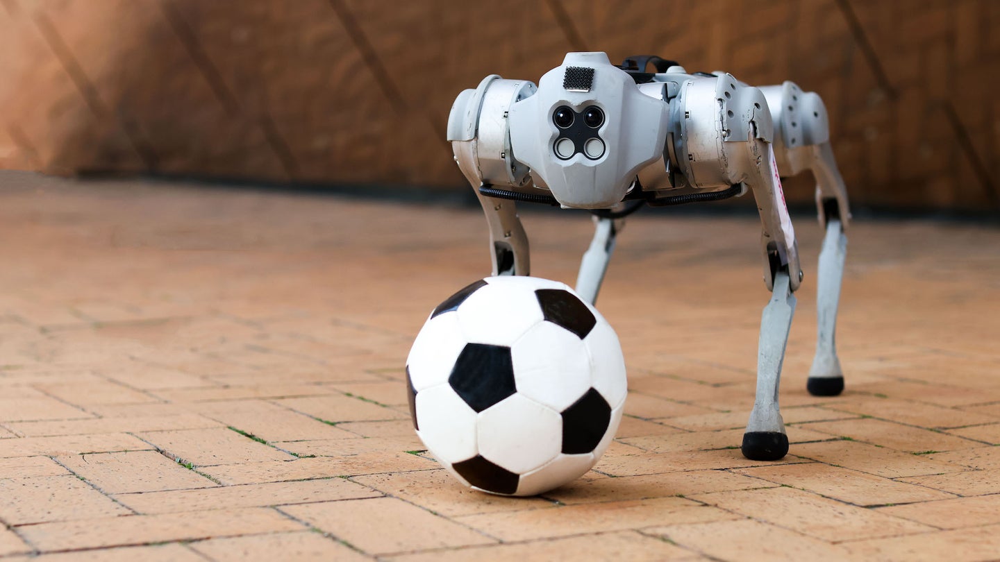 DribbleBot four-legged robot standing behind soccer ball