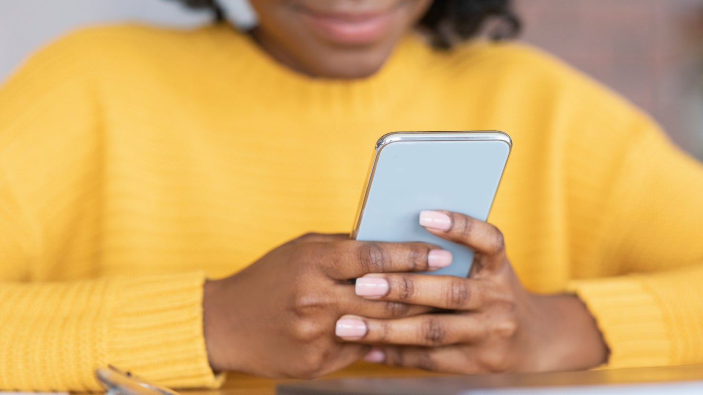 Cropped close-up of African American woman holding smartphone