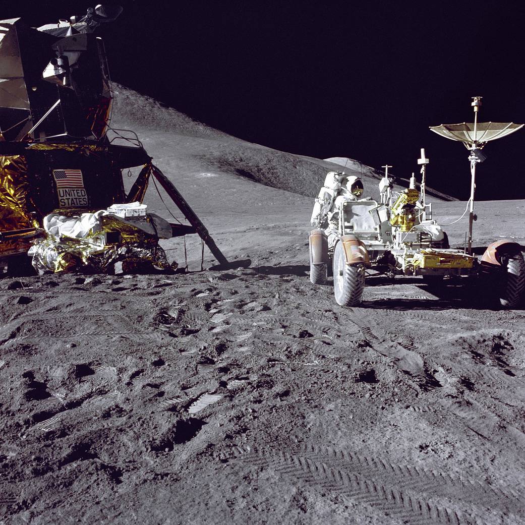 Apollo 15 astronauts driving lunar rover across moon crater