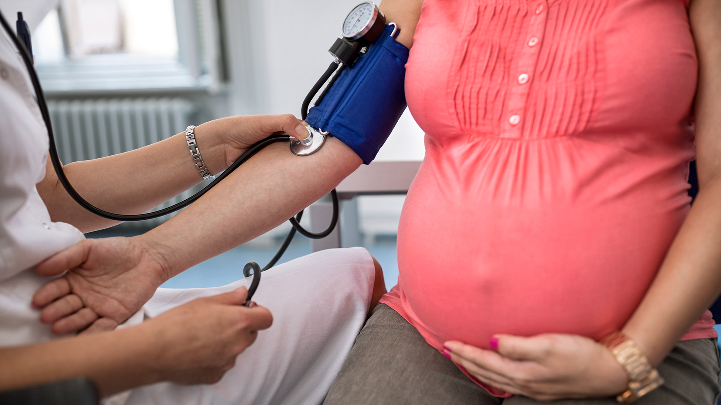 A pregnant patient gets a blood pressure reading in a medical setting.