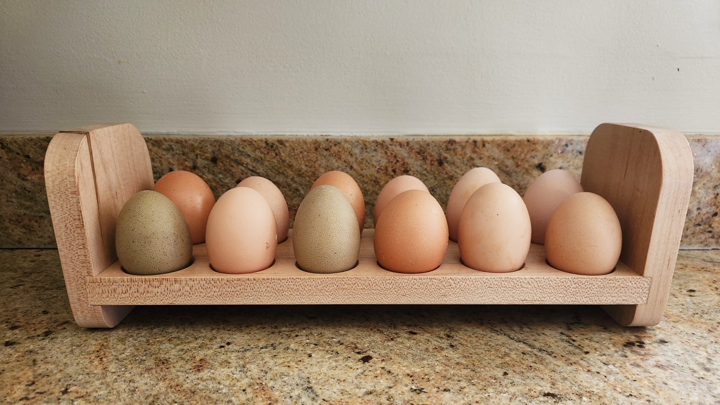 Twelve fresh eggs in a DIY wooden egg holder on a granite countertop.