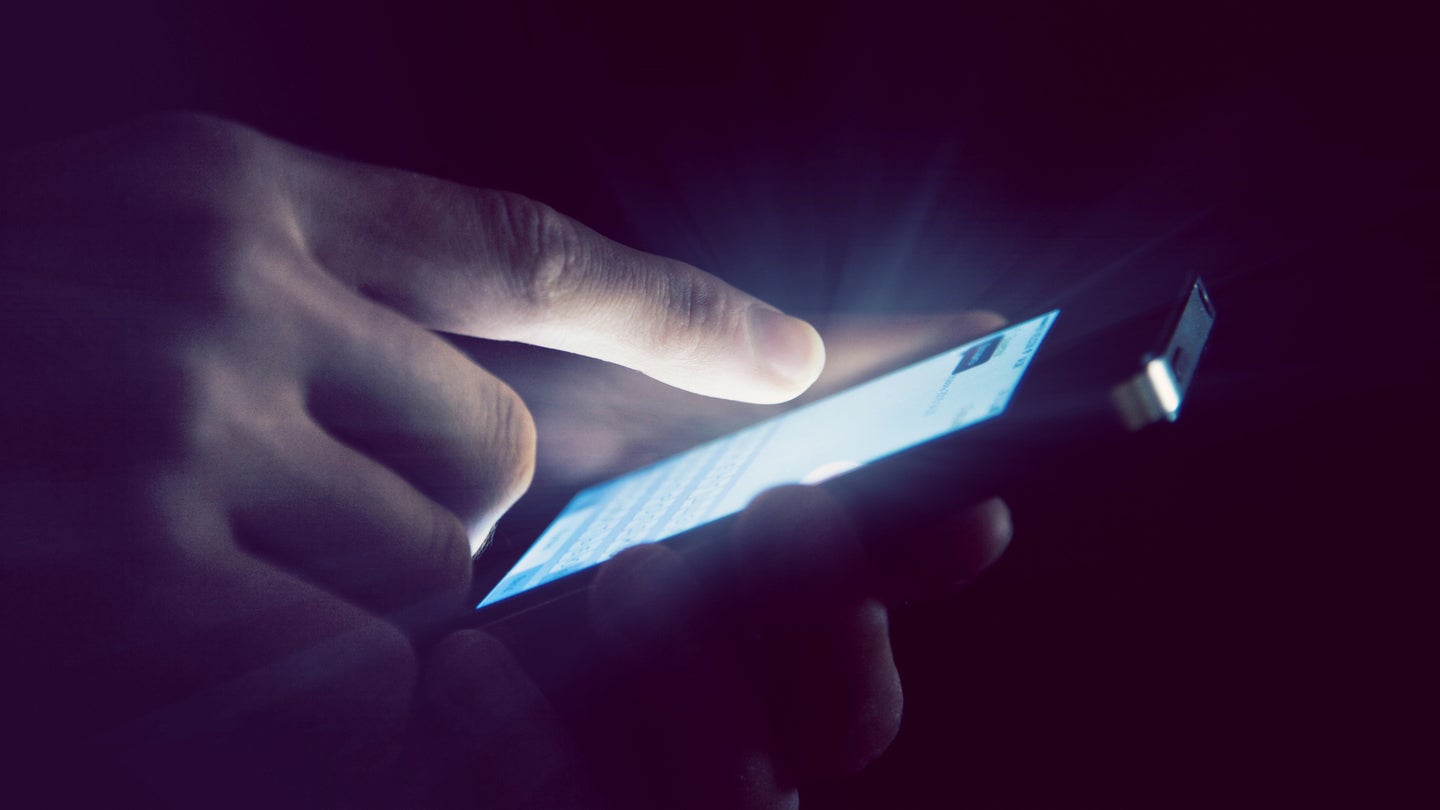 Hands holding and using smartphone in night light