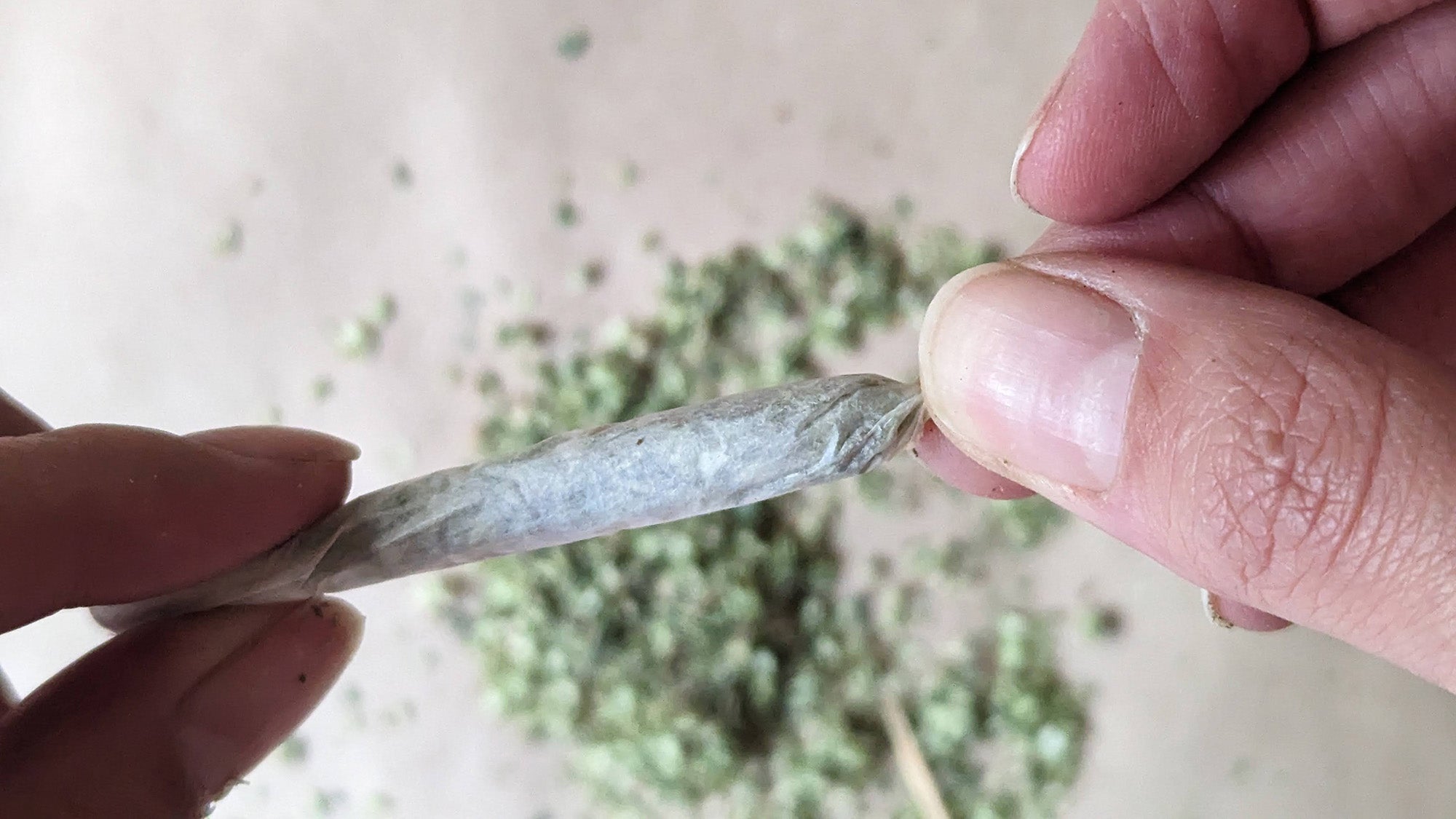 Hand holding a joint while the other twists the tip. 