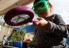 Toddler in green goggles holding a pink magnifying glass over a plant in a forest school in Los Angeles