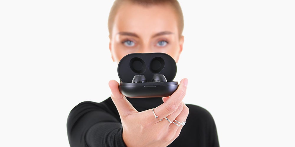 A woman holding a pair of wireless translation headphones