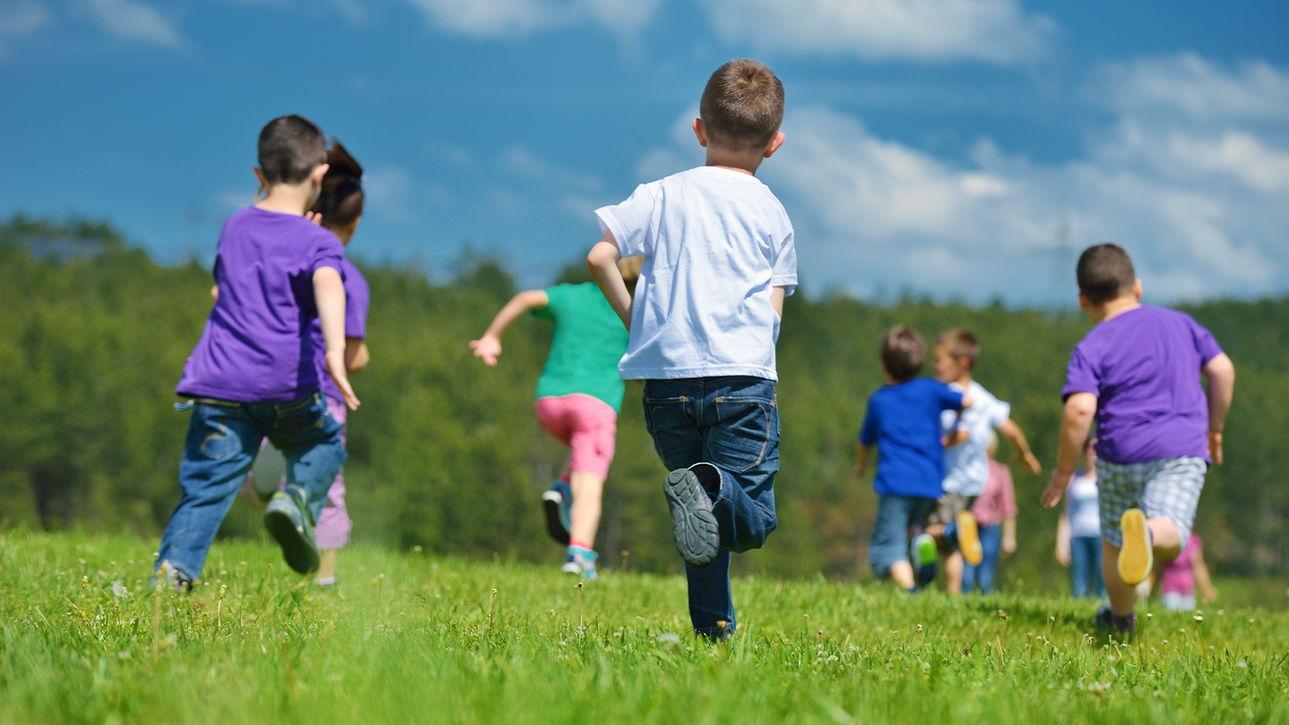 A group of eight children running in an open field.