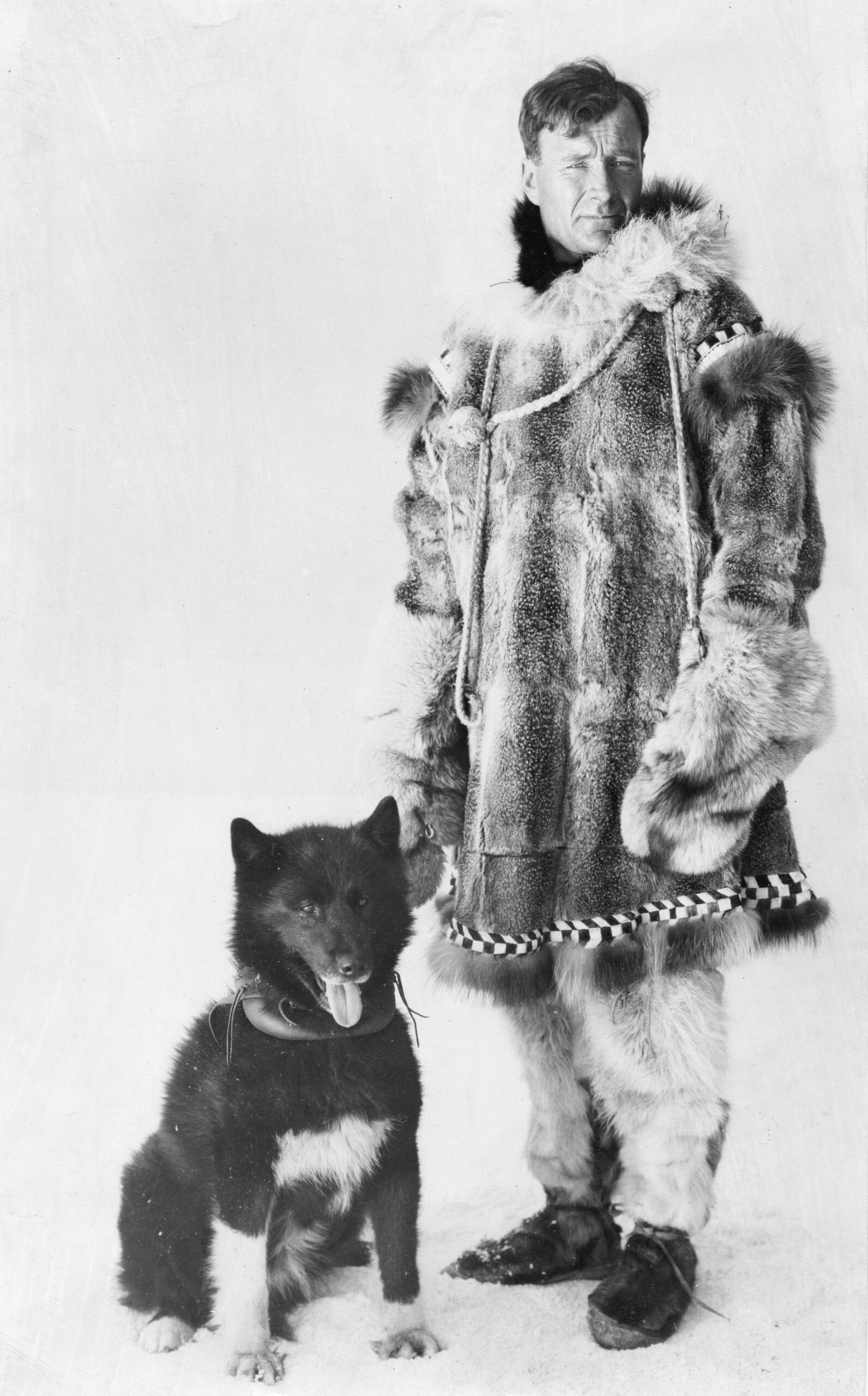 An archival photograph of famed sled dog Balto standing in the snow with his owner Gunnar Kasson.