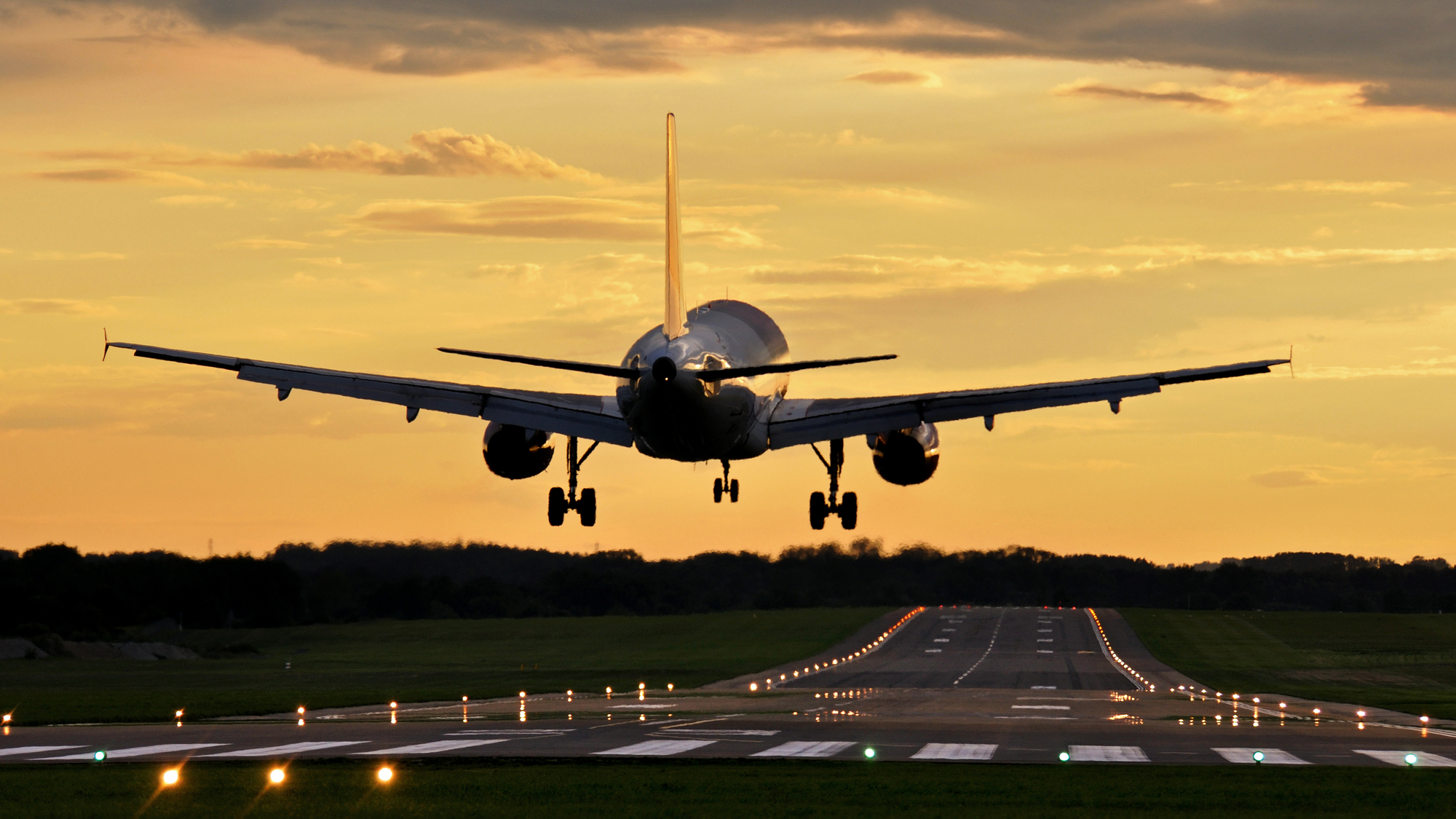Airplane landing on runway at sunset