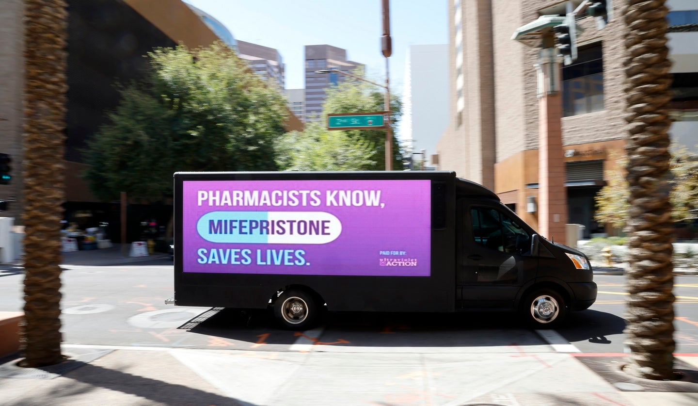 Black truck with purple screen that says "pharmacists know mifepristone saves lives" driving around Phoenix during abortion pill lawsuits