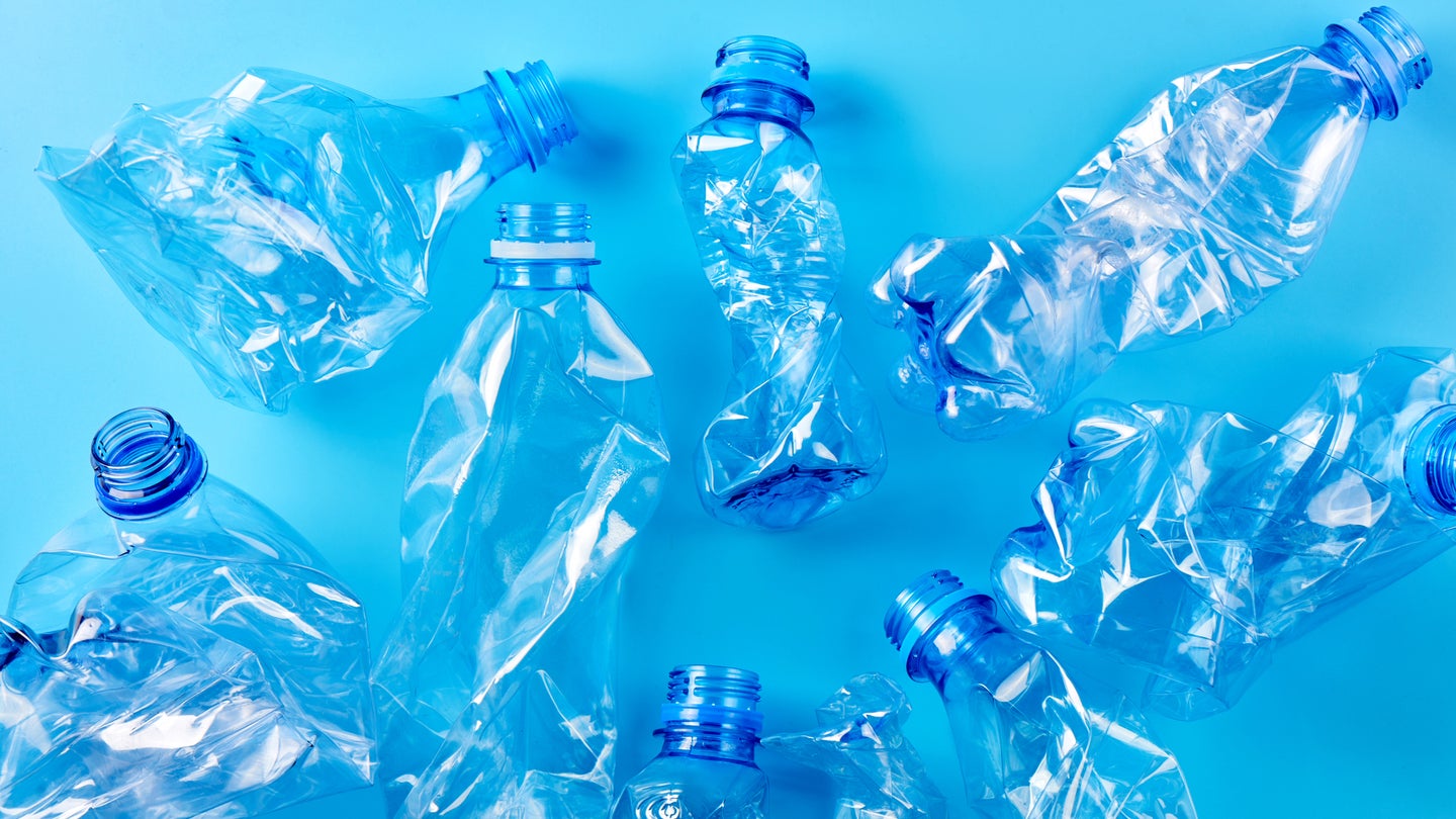 Empty crumpled plastic bottles pattern on blue background.