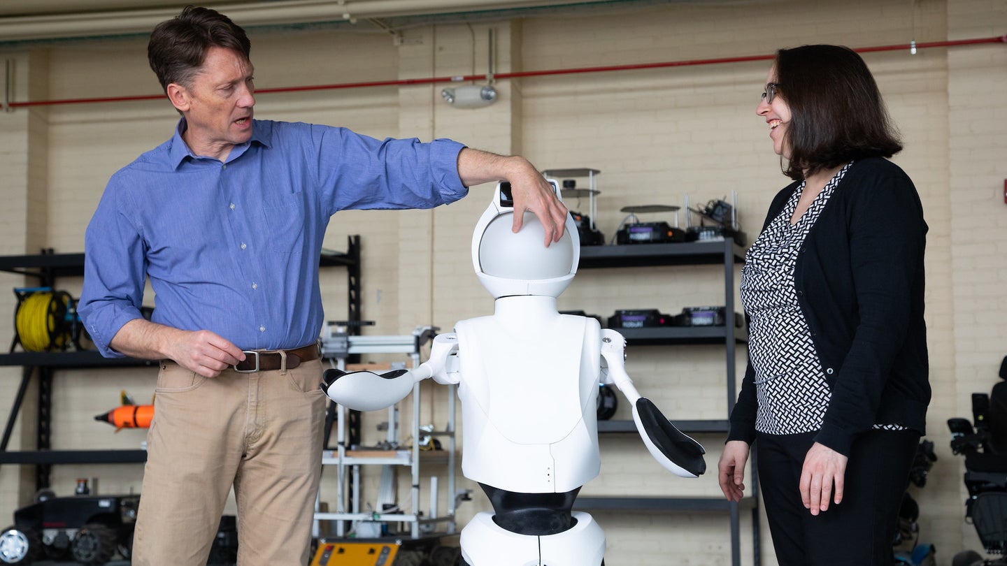 Two researchers standing next to Quori humanoid robot