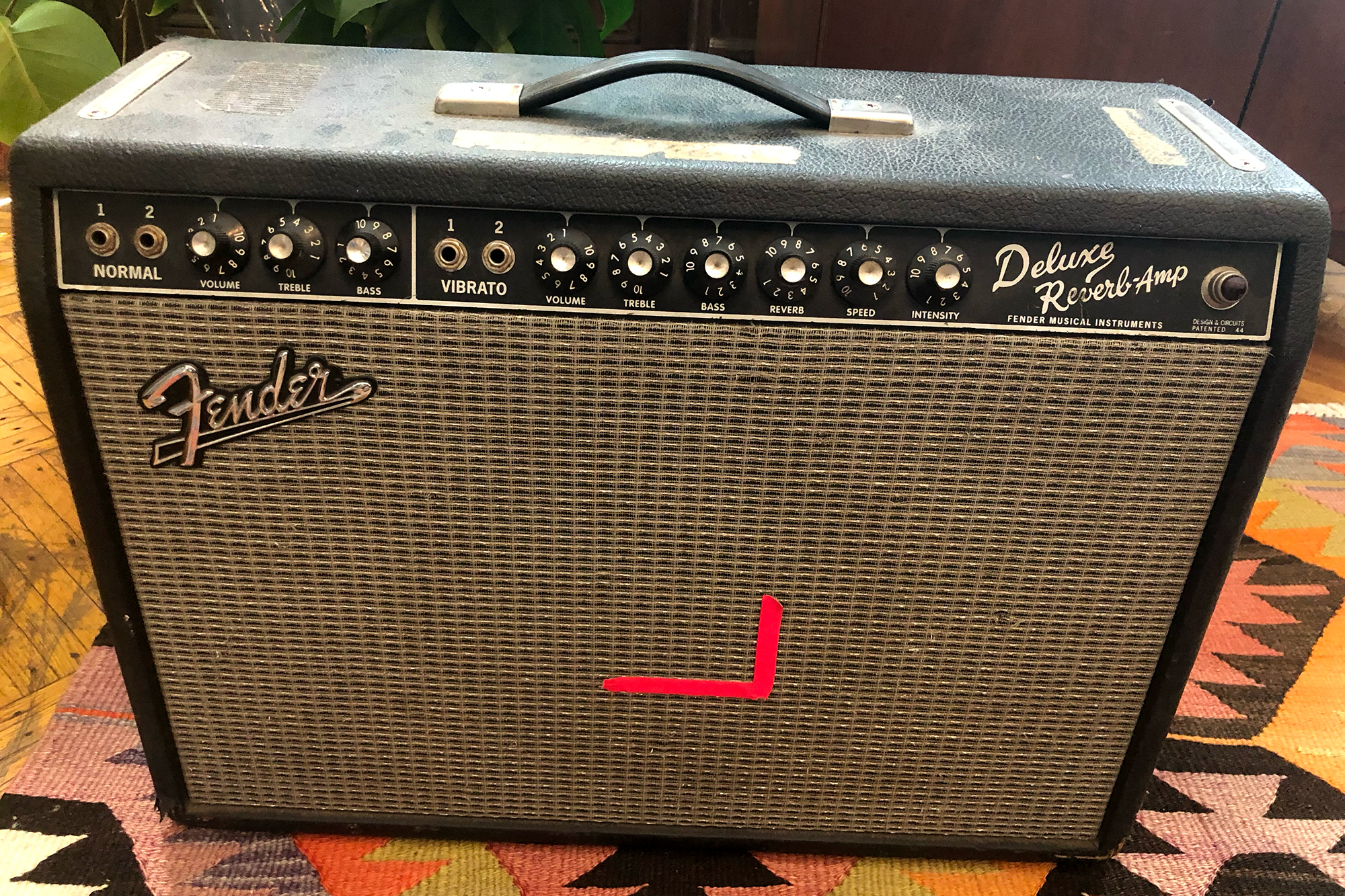 Beat-up Fender Deluxe Reverb guitar amp on a Southwestern carpet